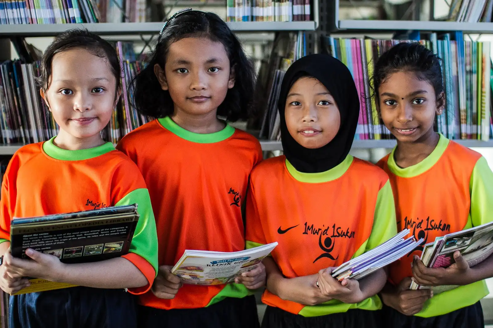 Four primary school girls in a library holding their reading books