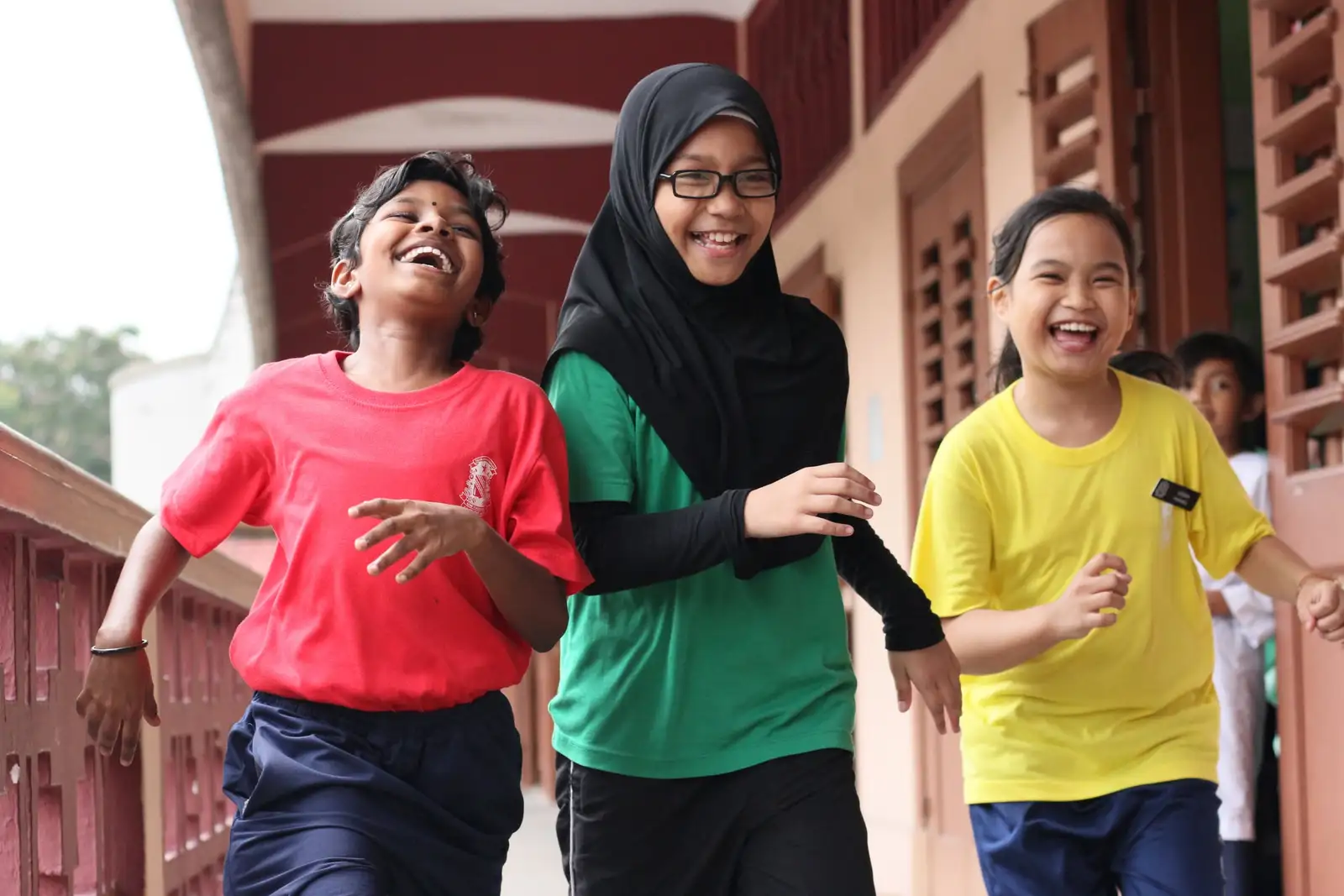 Three pupils laughing as they walk along a school corridor