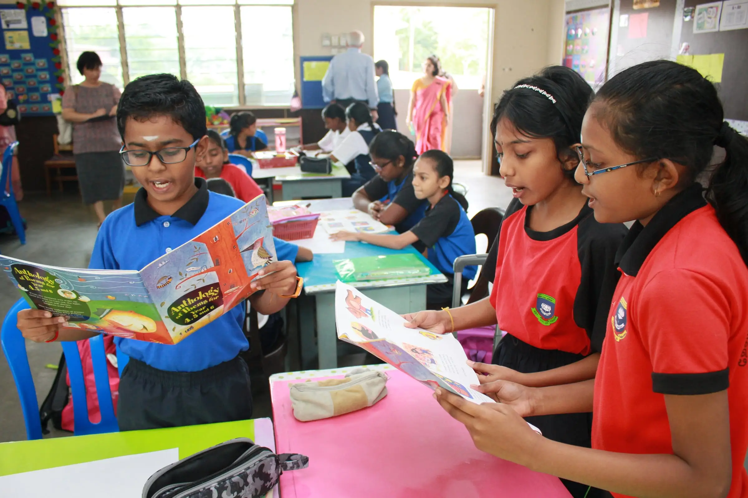 Primary pupils reading picture books at their desks