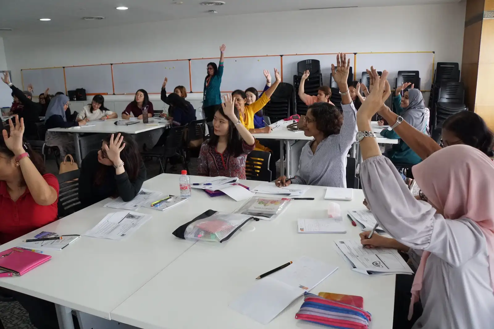 Teachers at a training workshop raising their hands to answer a question